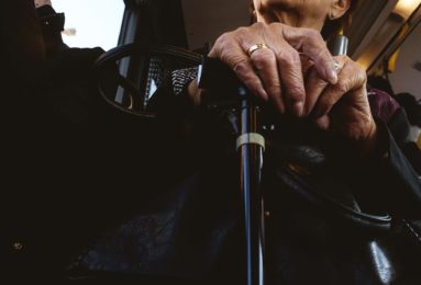 An older person's hands rest on top of a walking aid.