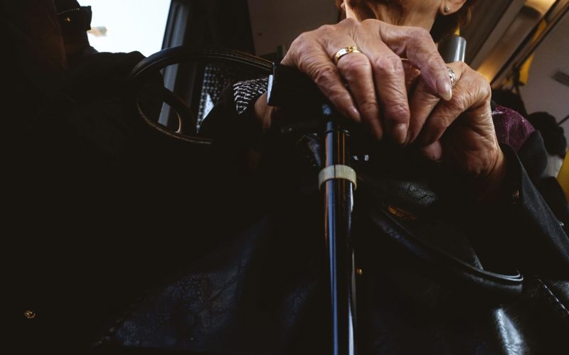 An older person's hands rest on top of a walking aid.