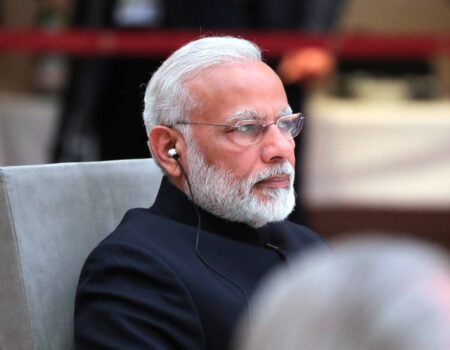 The Prime Minister of India, Modi, is shown sitting.