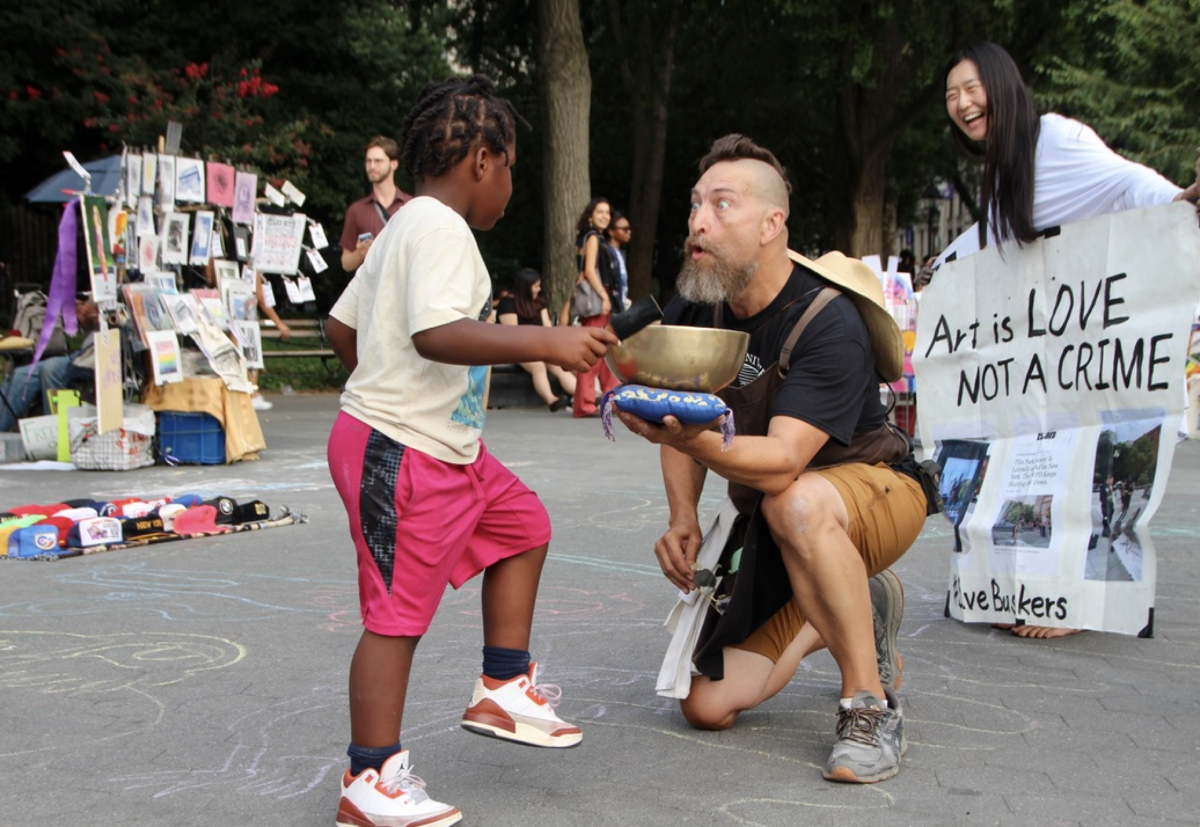 A child rings a singing bowl during a “Butterfly Revolution” protest in Washington Square Park. (Credit: Mukta Joshi)