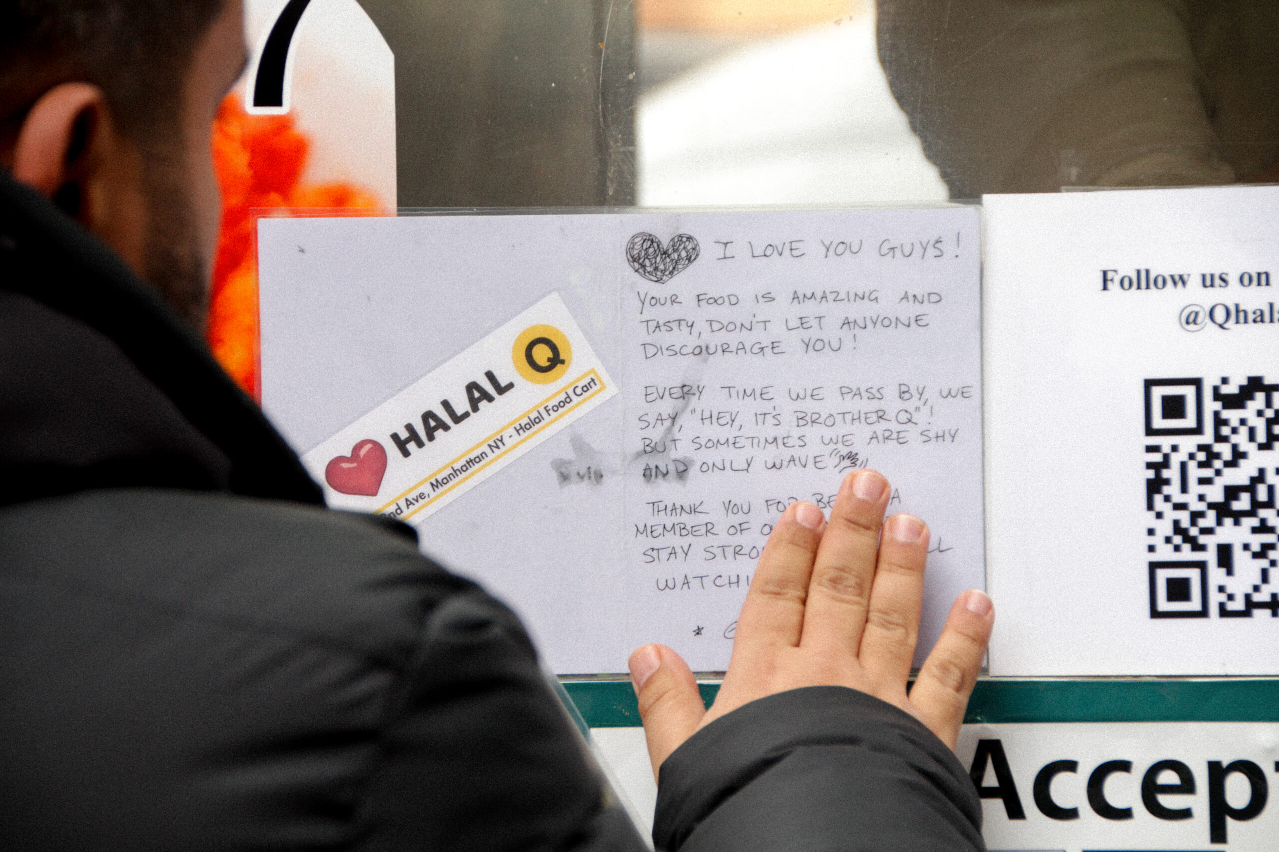 Islam Moustafa, 41, co-owner of Adam Halal Cart, props up a laminated card from a customer on the window of the Halal Cart. “Stay strong,” it says. “We are all watching.” (Credit: Mukta Joshi)