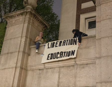 Two protestors put up a banner at Hamilton Hall after they occupied the building. (Credit: Indy Scholtens)