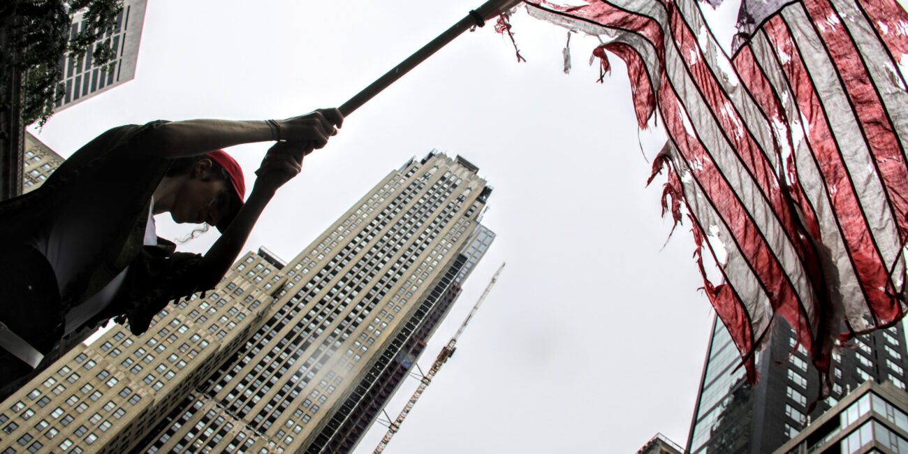 A demonstrator waves a tattered American Flag during the 'No Kings' Protest in New York City. (Credit: Abbie Hopson)