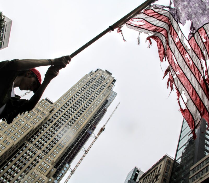 A demonstrator waves a tattered American Flag during the 'No Kings' Protest in New York City. (Credit: Abbie Hopson)