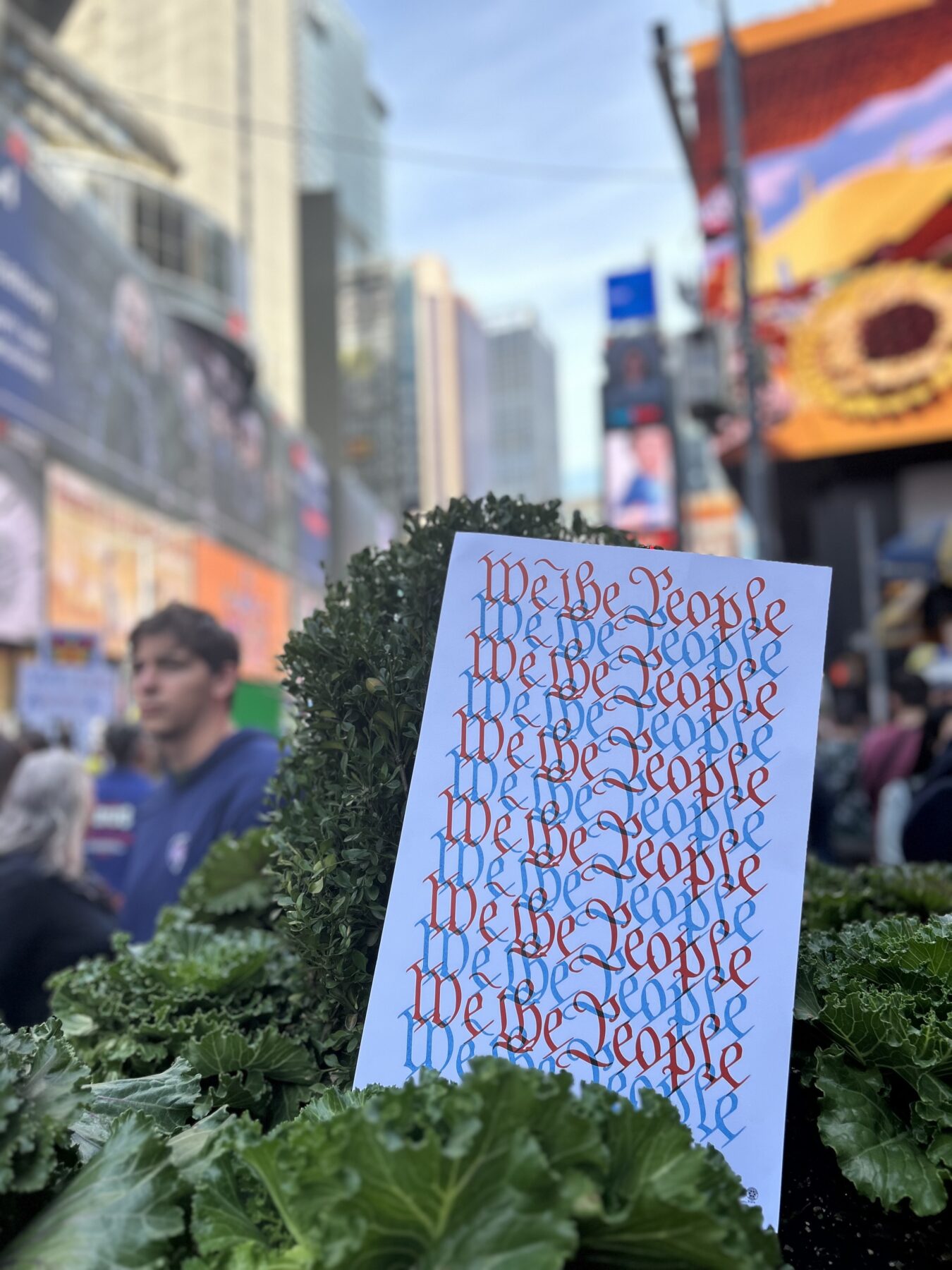 A “We the People” sign left behind in a bush by a protester in Times Square on Oct. 18. (Credit: Hannah Smith)