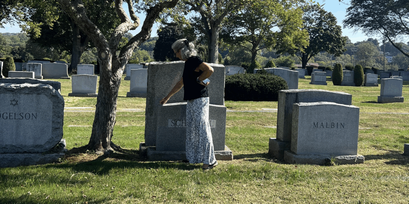 Amy Schimmel, 69, at Sharon Gardens Cemetery in Westchester, NY, where she places a stone on the headstone of her aunt and uncle. Sept. 15, 2025. (Credit: Mia Anzalone)