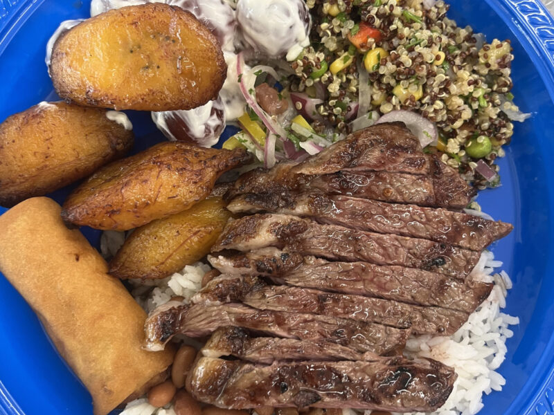 A plate from Rio Market’s buffet section featuring picanha﻿, a popular Brazilian grilled beef cut, served with white rice, beans, quinoa salad, fried plantains, and more. (Credit: Noa Metta)