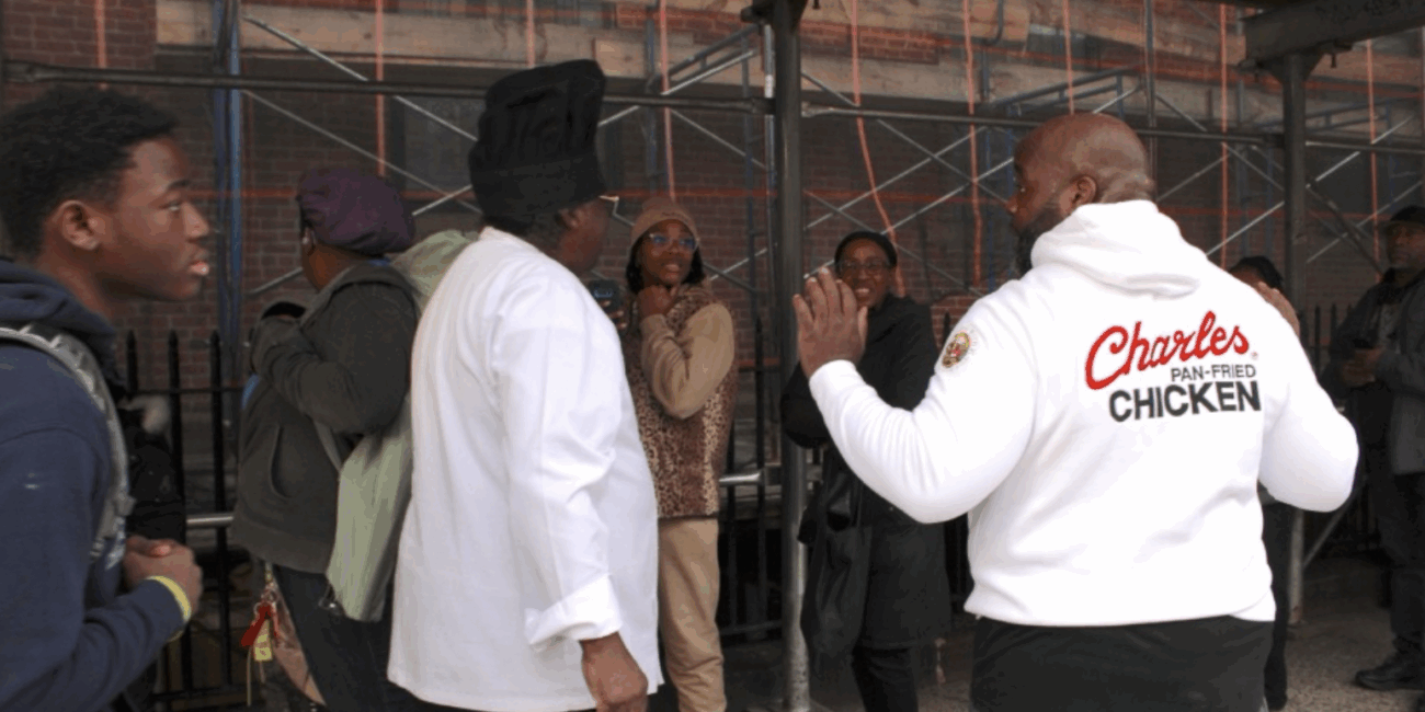 Charles Gabriel (left), the founder of Charles Pan-Fried Chicken, and Chief Operations Officer Chef Quie Slobert (right) chat with people in line for free meals at Saint Joseph’s Church in Harlem. (Credit: Anna Lee)