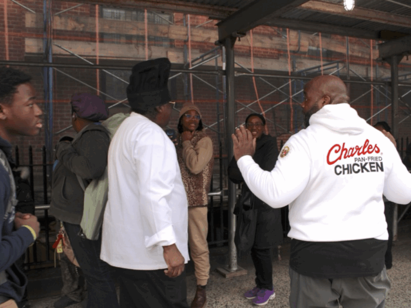 Charles Gabriel (left), the founder of Charles Pan-Fried Chicken, and Chief Operations Officer Chef Quie Slobert (right) chat with people in line for free meals at Saint Joseph’s Church in Harlem. (Credit: Anna Lee)
