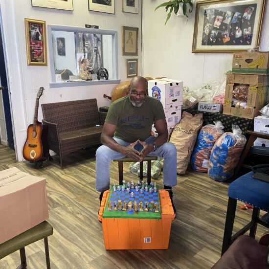 Cassius "Cash" Watson sits with "ENCIDIUS", a board game he designed, at E.T.A. Universal Outreach, a community center in Crown Heights that he operates with his sister. (Credit: Sophie Holin)