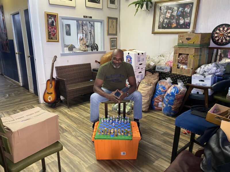 Cassius "Cash" Watson sits with "ENCIDIUS", a board game he designed, at E.T.A. Universal Outreach, a community center in Crown Heights that he operates with his sister. (Credit: Sophie Holin)