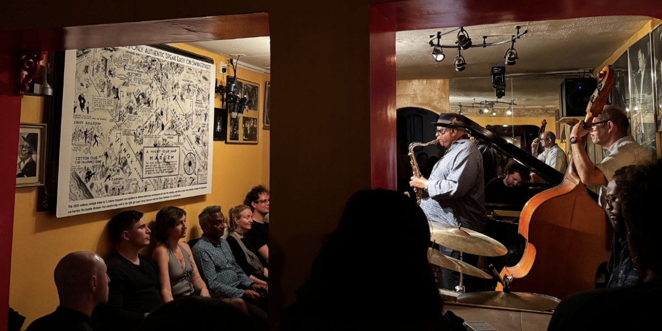 Bill Saxton plays the saxophone facing 1932 cartoon of Harlem streets replete with clubs. His is now the last authentic jazz club in the area.(Credit: Ana Federica Wallis)
