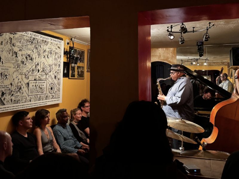 Bill Saxton plays the saxophone facing 1932 cartoon of Harlem streets replete with clubs. His is now the last authentic jazz club in the area.(Credit: Ana Federica Wallis)