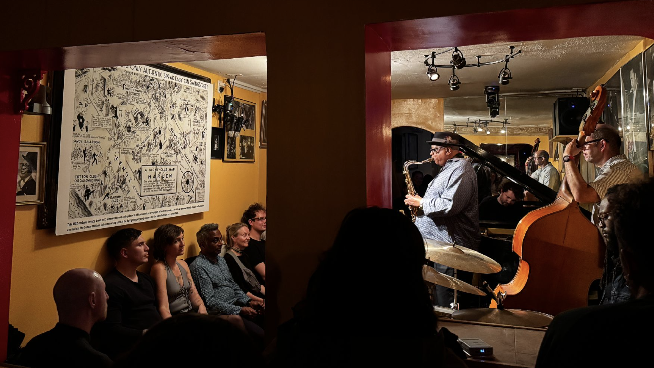 Bill Saxton plays the saxophone facing 1932 cartoon of Harlem streets replete with clubs. His is now the last authentic jazz club in the area.(Credit: Ana Federica Wallis)